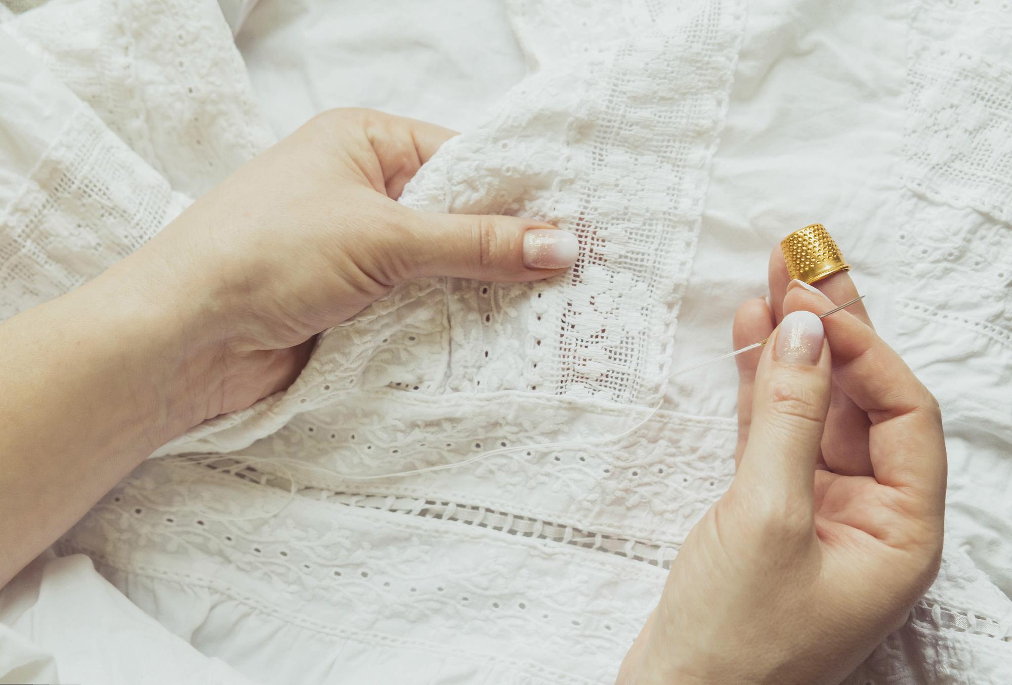 Artisan arranging embroidered samples on wooden table