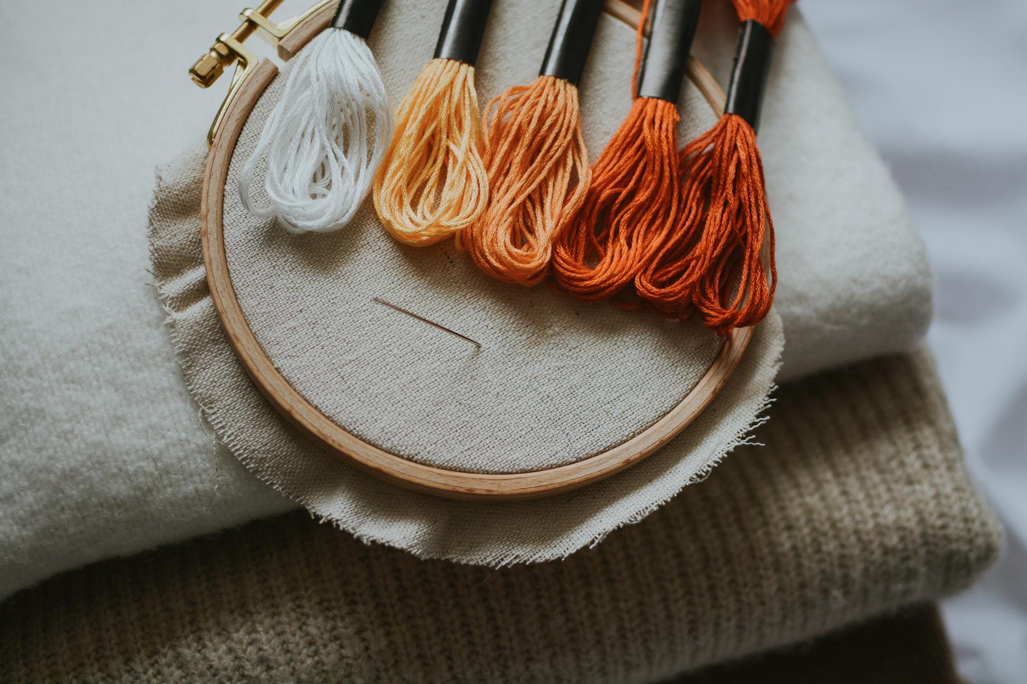 Close-up of hand and machine embroidery on linen with terracotta tones
